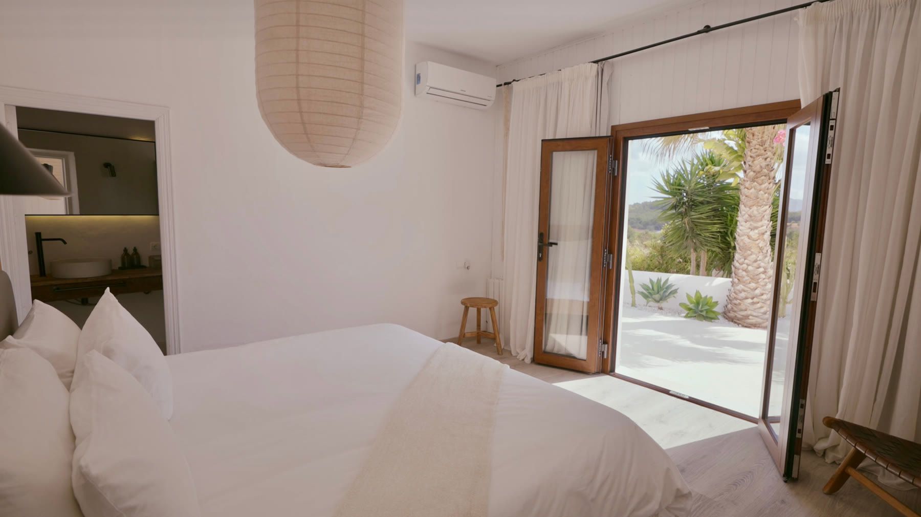The master suite, opening onto its private white terrace among the palms